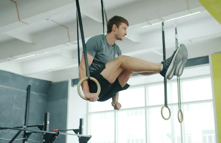 Gimnastičar vežba na karikama u sportskoj sali