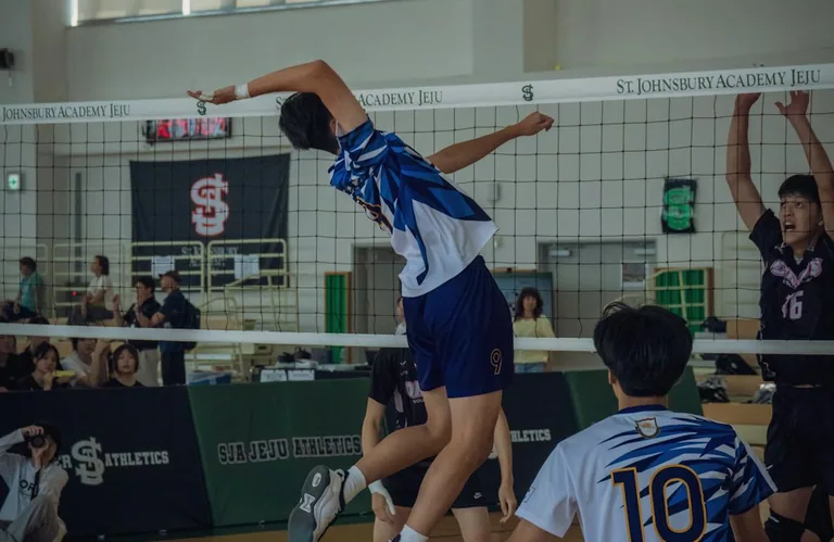 Mladi igraju odbojku u školskoj sportskoj sali